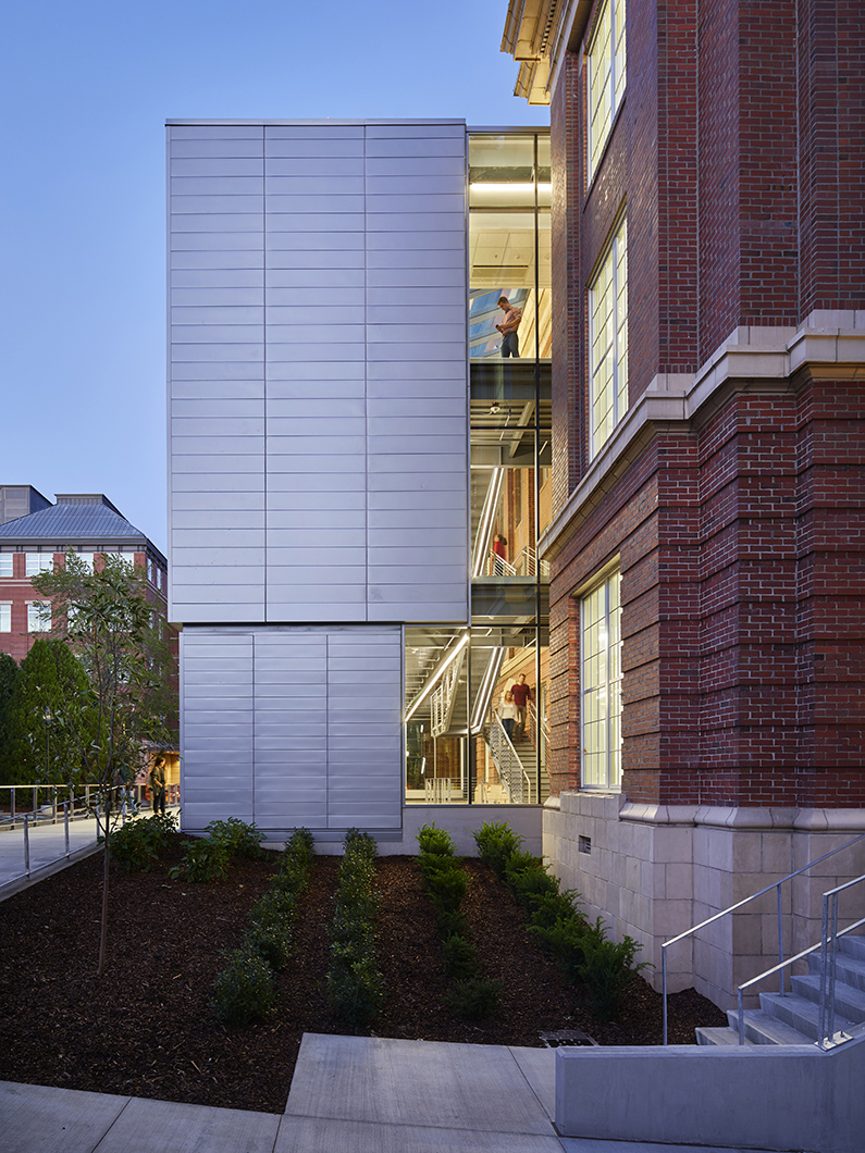 New glass addition juts out from historic building with views to interior stair and atrium
