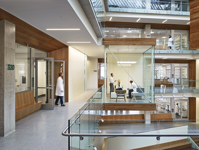 Employees conversing in collaboration pod that juts out into the atrium of the Allen Institute