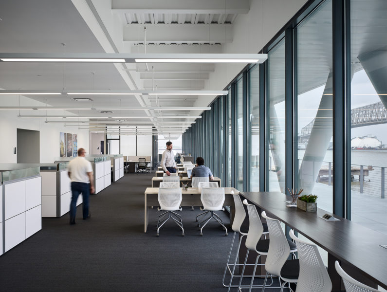 Co-working space with half-walls, open desks, and views to the river outside.