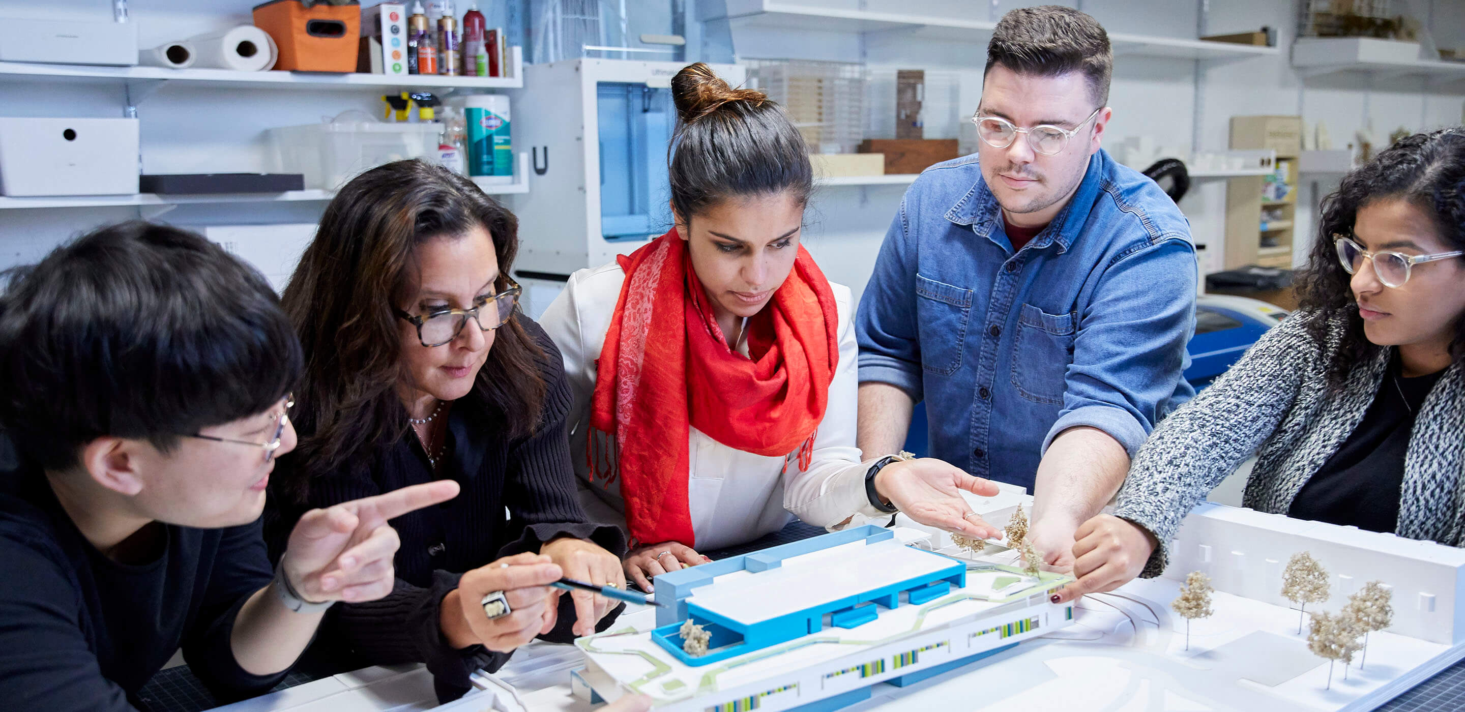 Photo of architects, designers, and public school officials looking at a 3D architectural model of a school