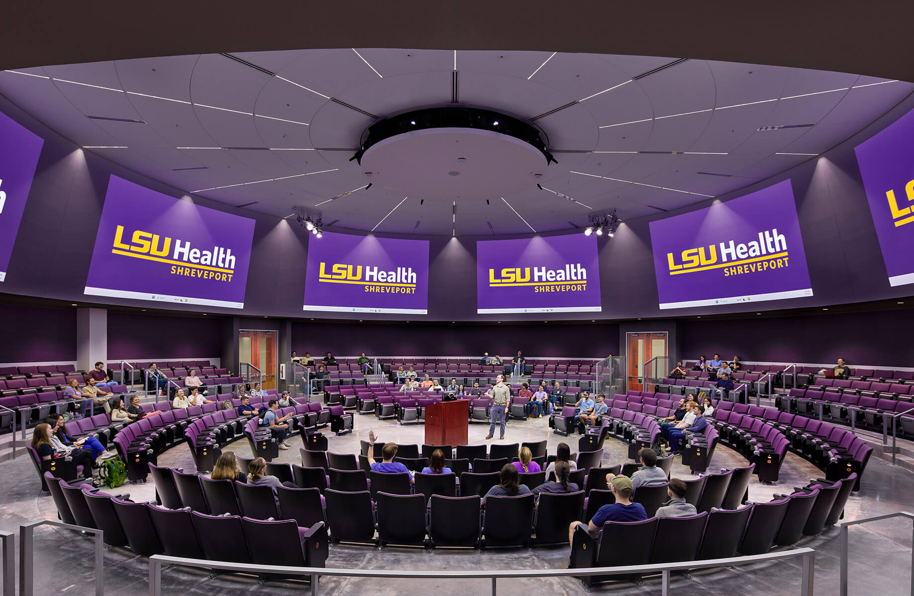 LSU Health Shreveport lecture hall with students in a modern amphitheater setting with screens.
