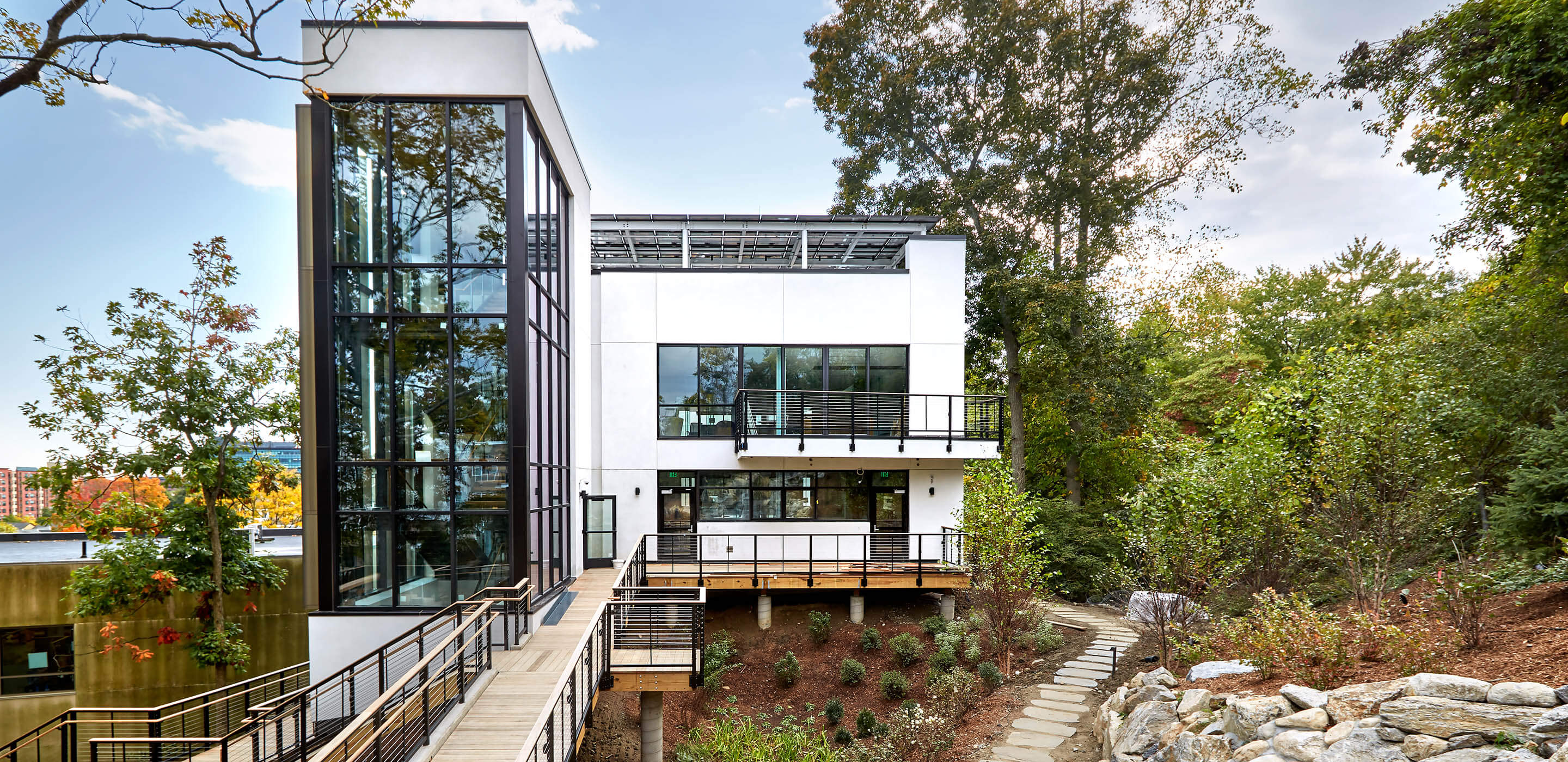 Photo showing corporate headquarters with forest paths, solar panels, and rain gardens.