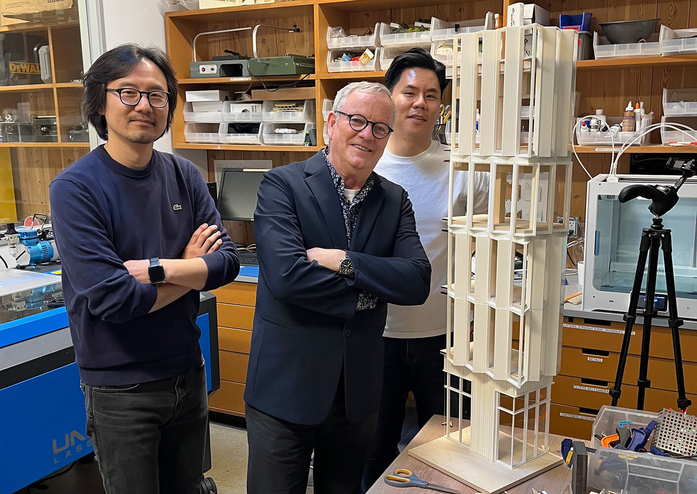 peter pfau smiles, arms crossed, in a model shop flanked by two other people