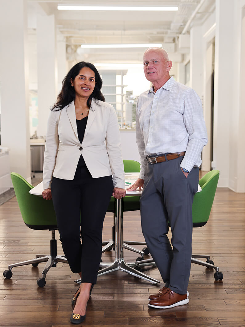 Nayak and Reisenbichler lean against a table next to one another smiling