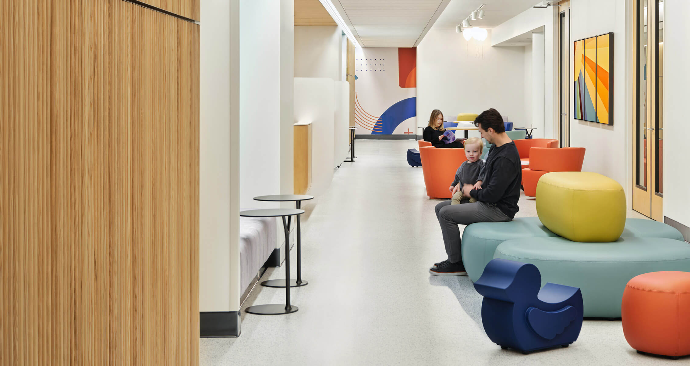 Bright, modern waiting area with colorful, round-edged seating including a child-sized seat shaped like a duck.