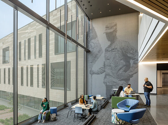 Modern office space with large windows, people collaborating and relaxing.