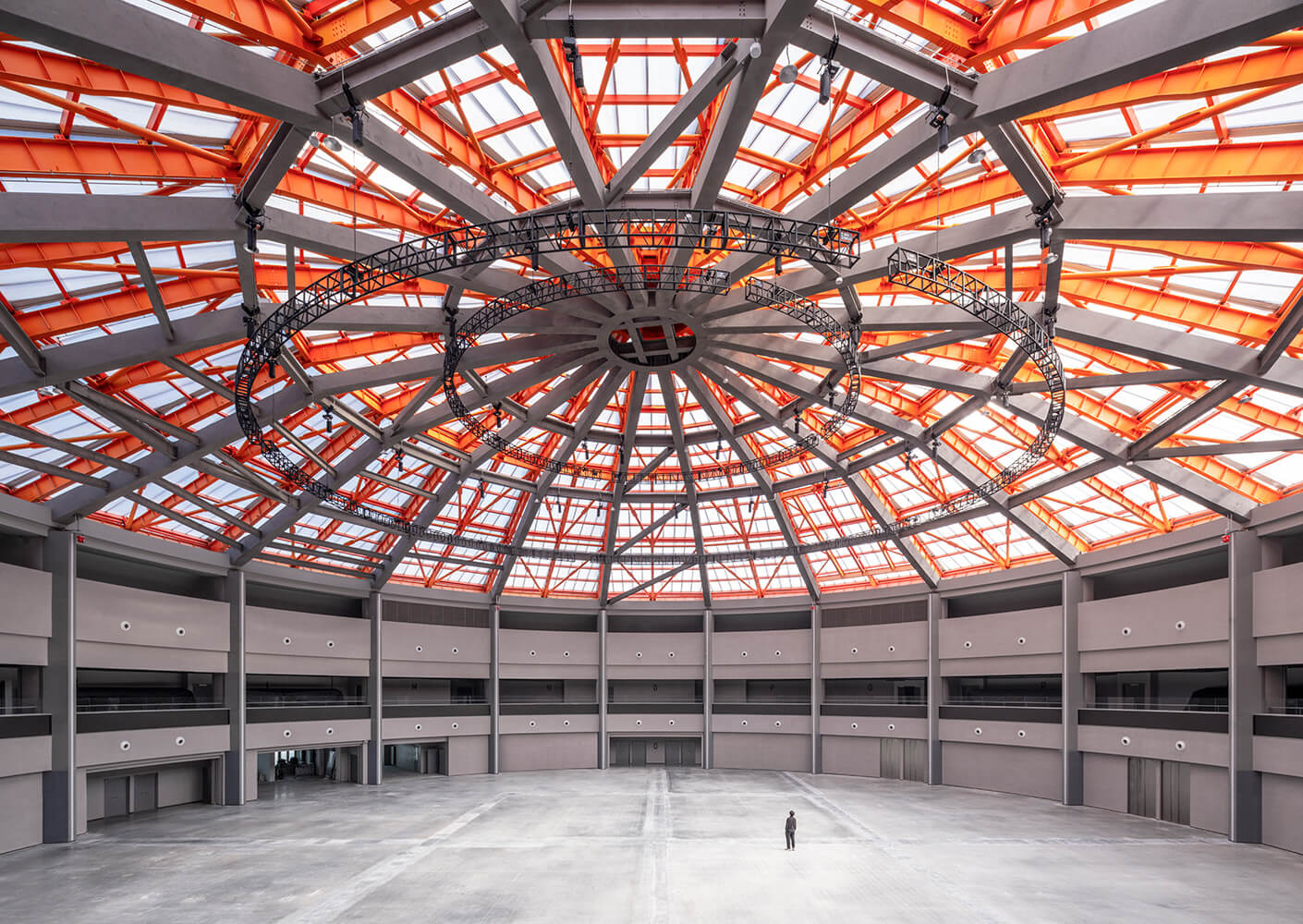 Spacious dome interior with geometric orange roof, showcasing a modern architectural structure.