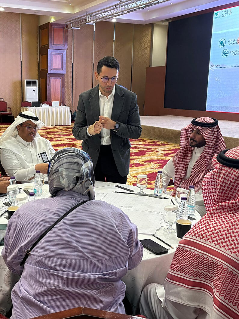 Business meeting with people in formal attire, discussing documents at a conference table.