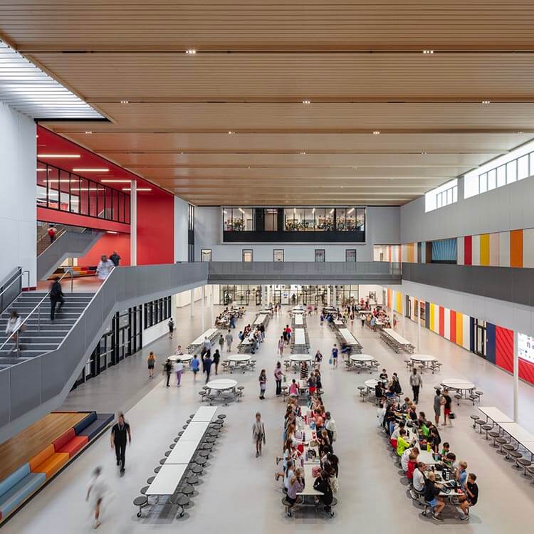Modern school cafeteria with students and staff in a spacious, colorful environment.