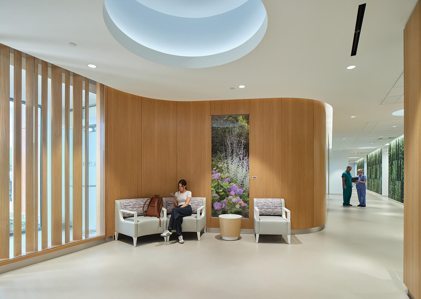 Modern clinic waiting area with wooden accents, seating, and a hallway lined with nature images.