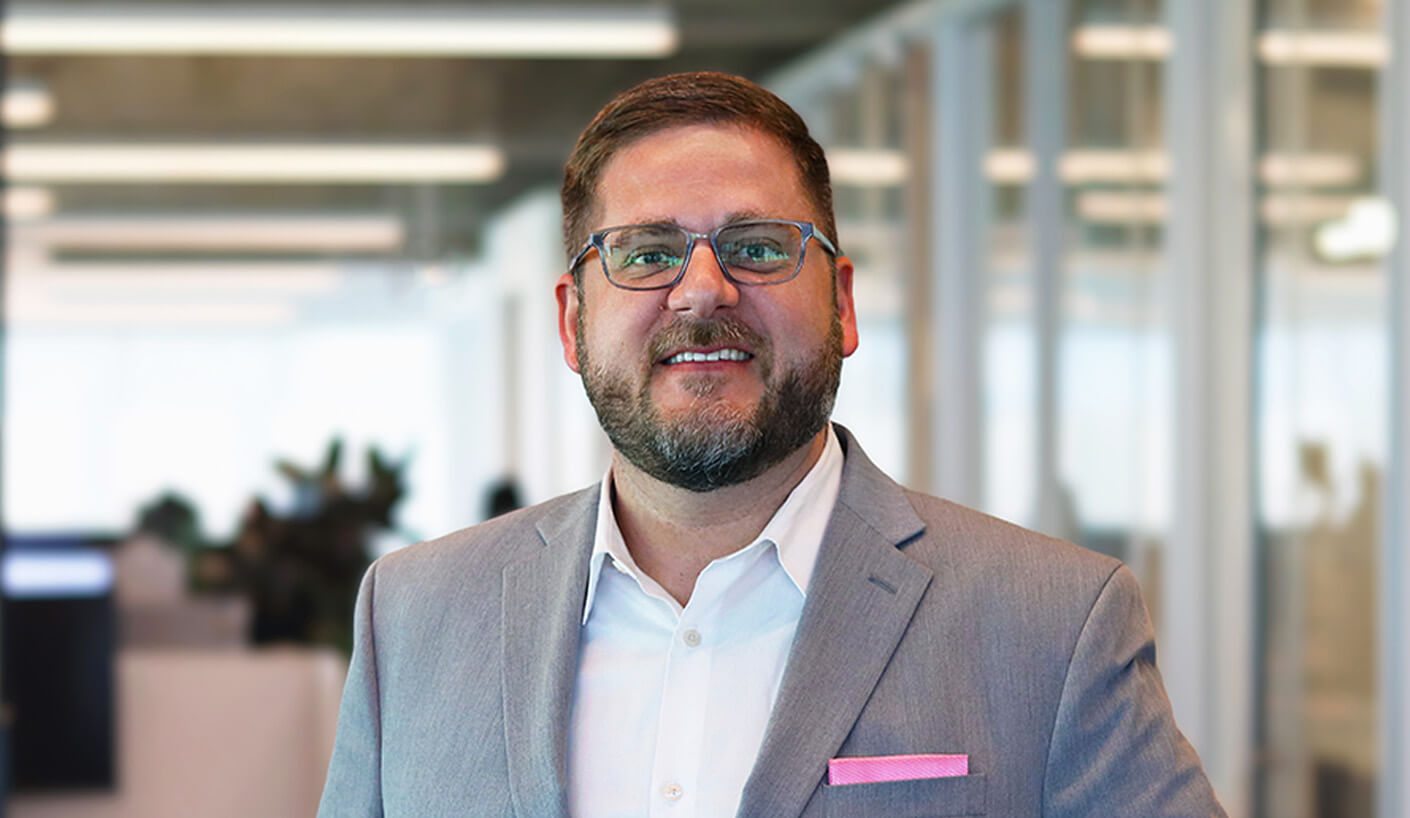 Professional man in a suit smiling in a modern office setting.