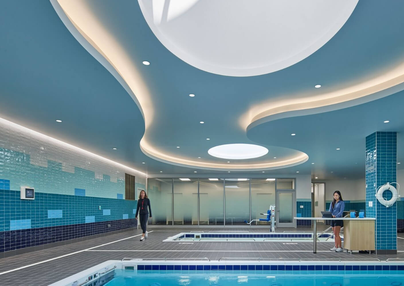 Indoor swimming pool with modern design and blue tiles. Fitness center environment.