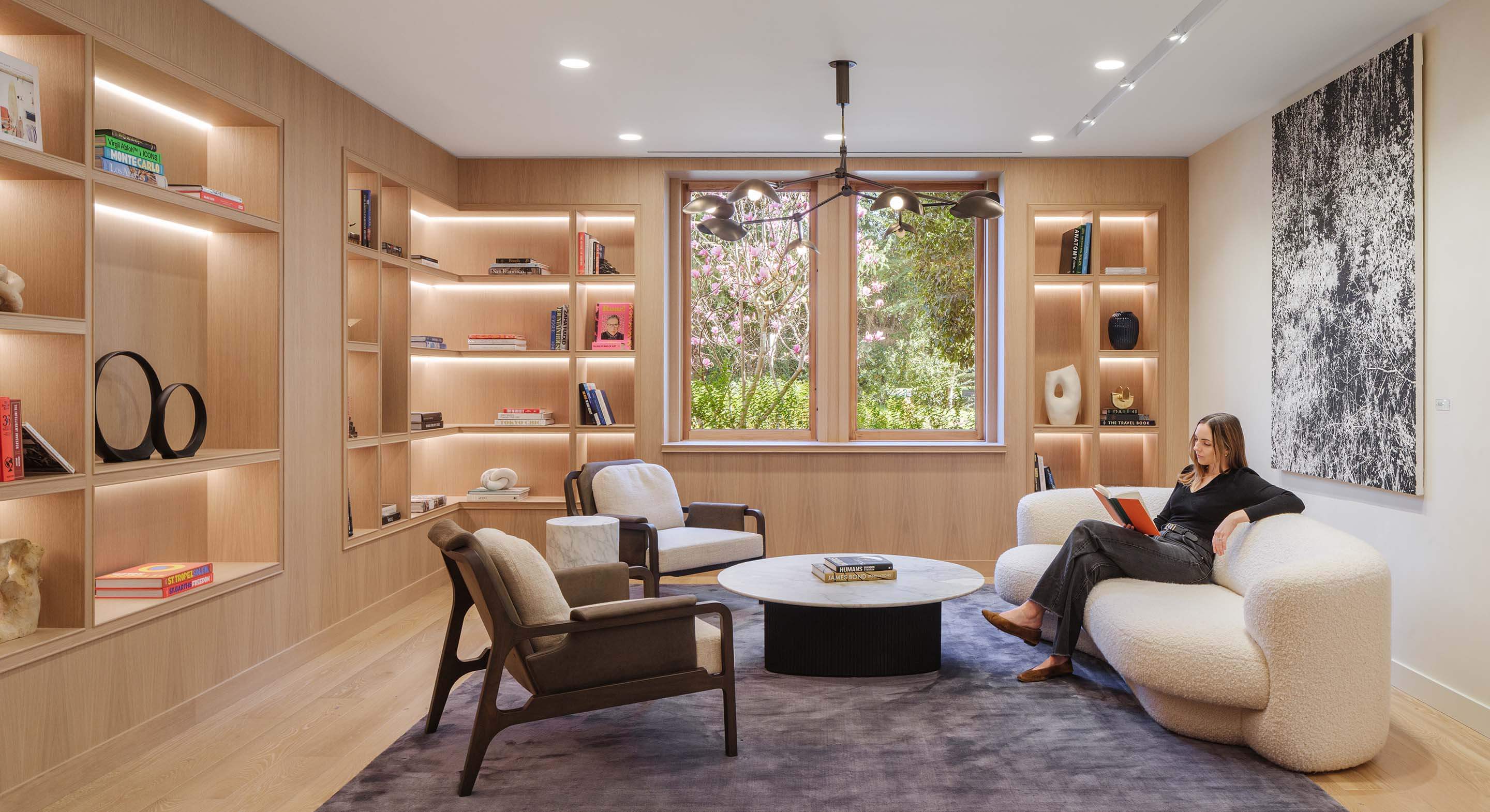 Modern reading room with wooden shelves and cozy seating.