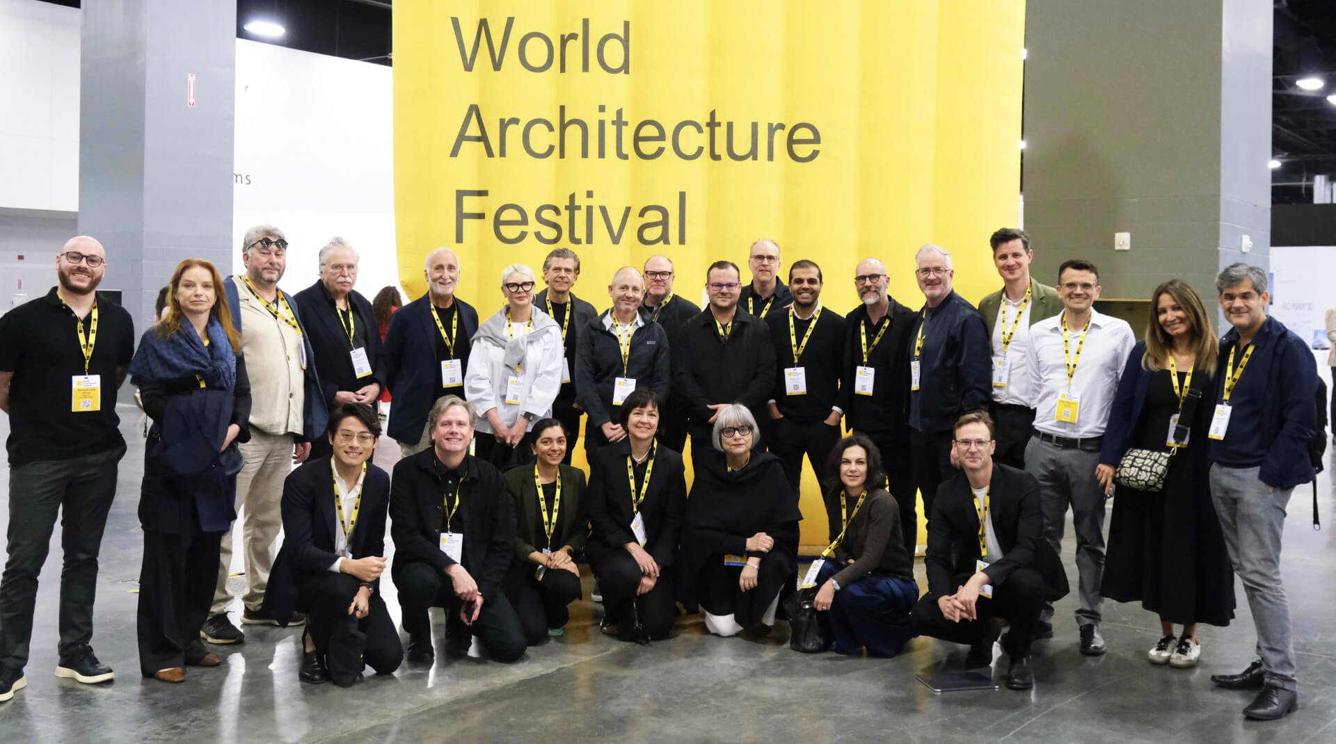 Group photo at World Architecture Festival, attendees smiling in front of yellow WAF banner.