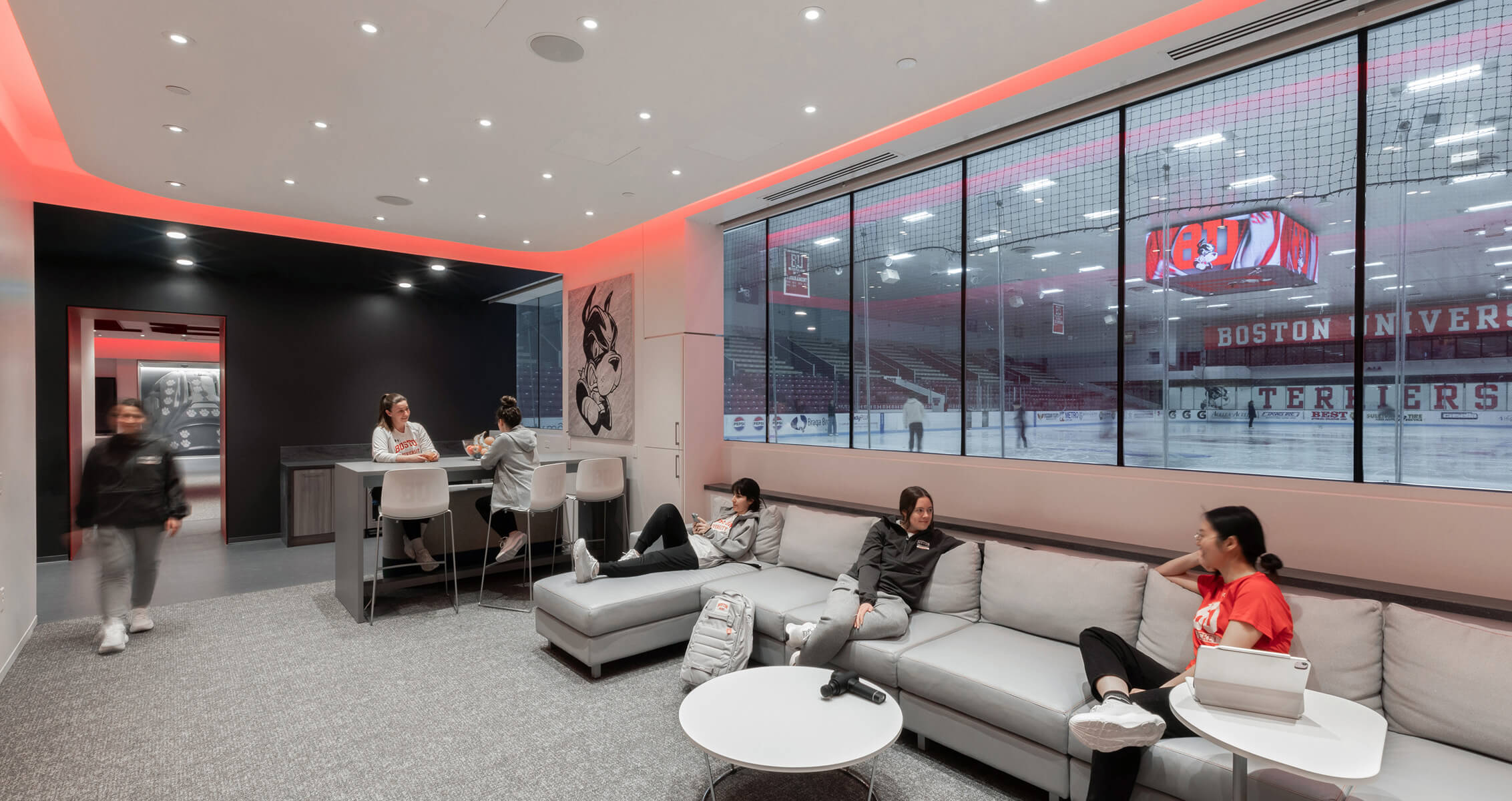 Cozy lounge with women ice hockey student-athletes overlooking Boston University hockey rink.
