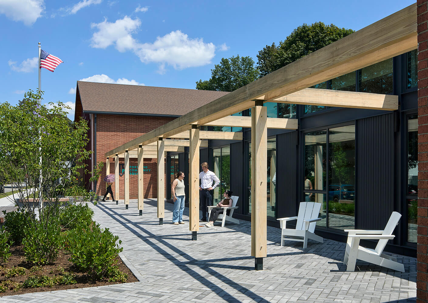 Squash community center with outdoor seating and visitors under a wooden pergola.