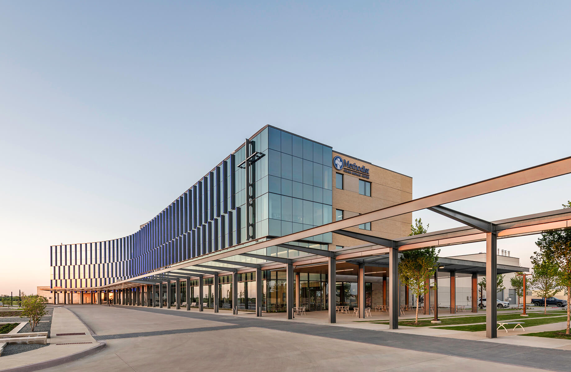 Modern hospital building exterior with glass facade under a clear sky.