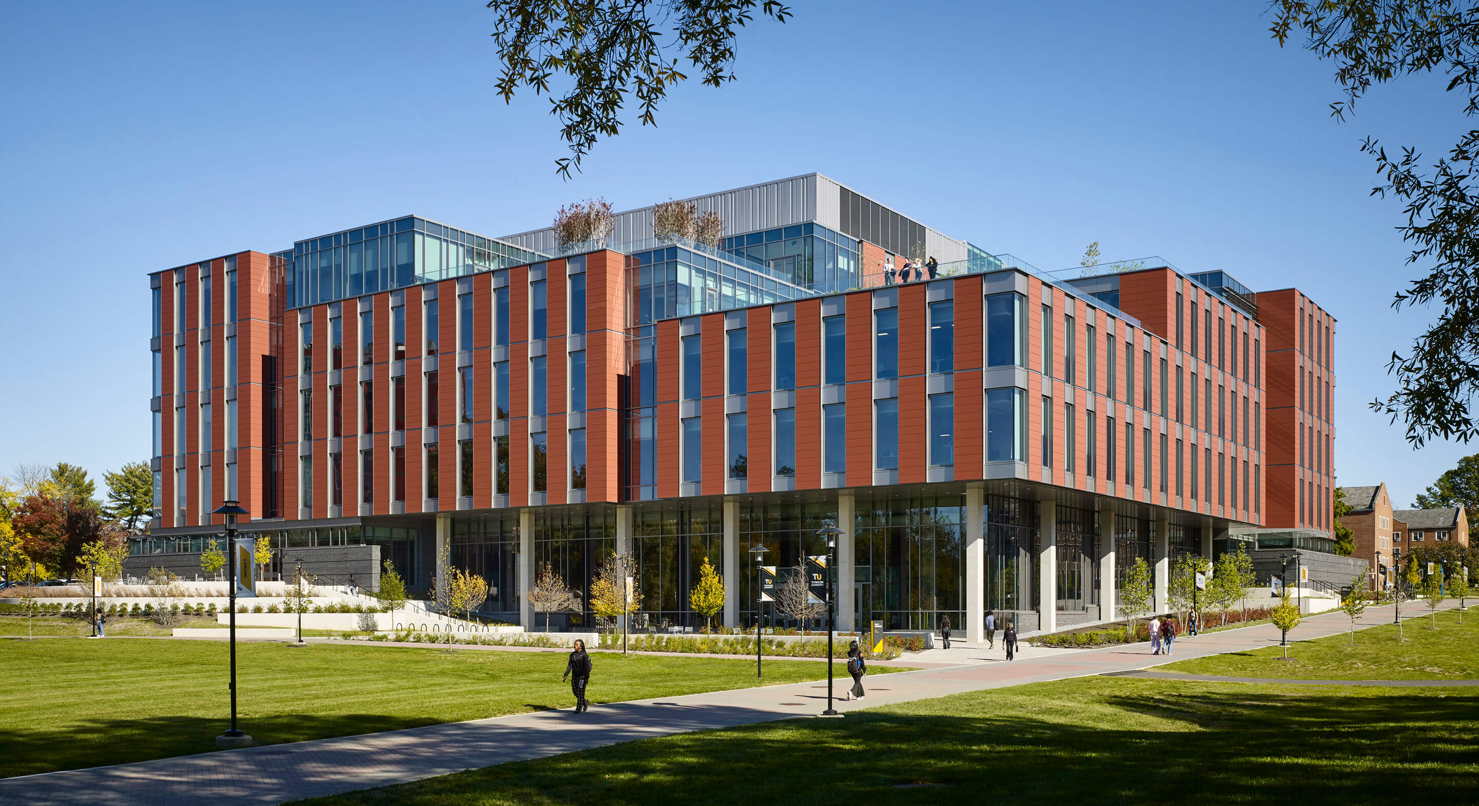 Modern brick and glass university building under clear blue sky.