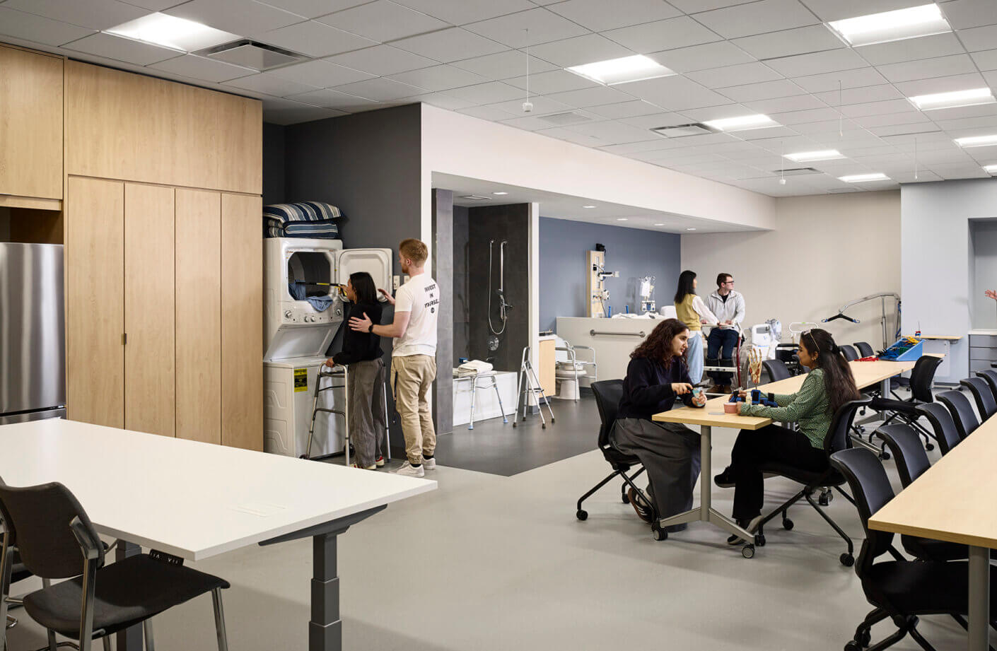Modern healthcare learning space with people using equipment and engaging in discussions.