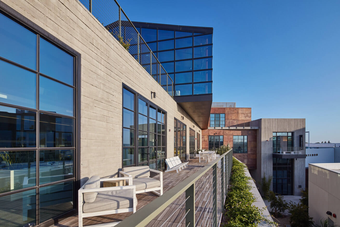 Modern office building with large windows and rooftop terrace on a clear day.