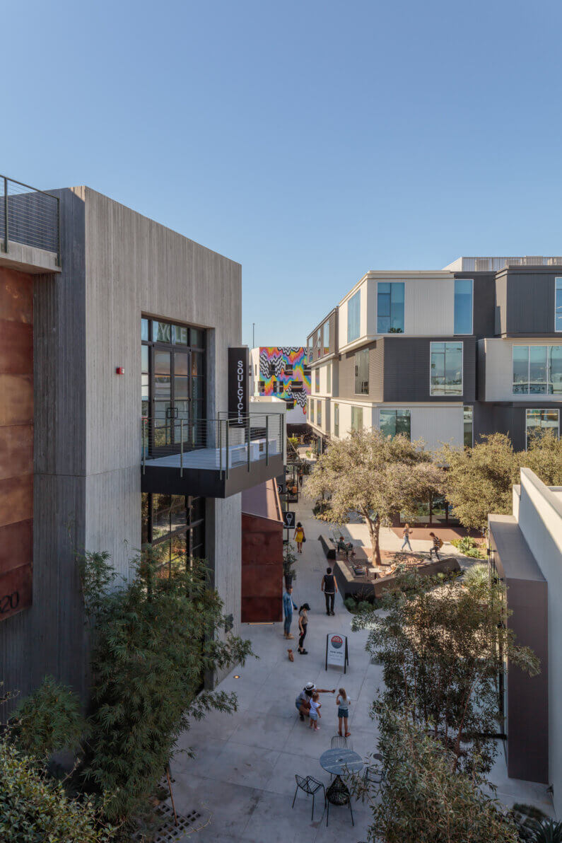 Modern urban plaza with people and contemporary architecture under a clear blue sky.
