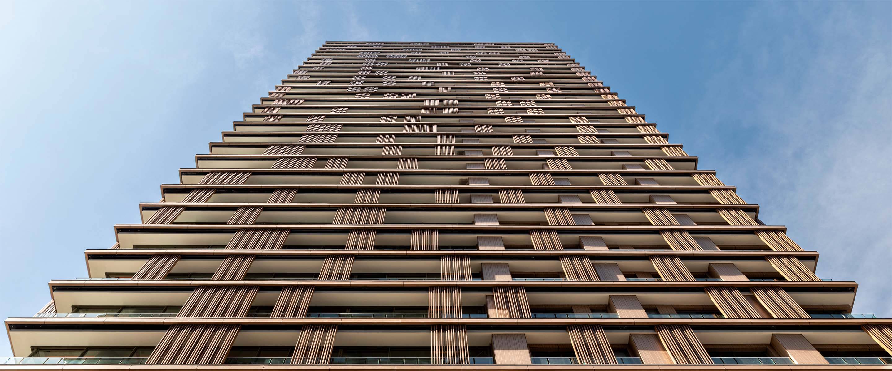 Tall modern building against a blue sky, showcasing architectural design.