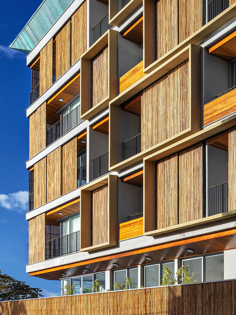 Modern building facade with wood panel details against a clear blue sky.