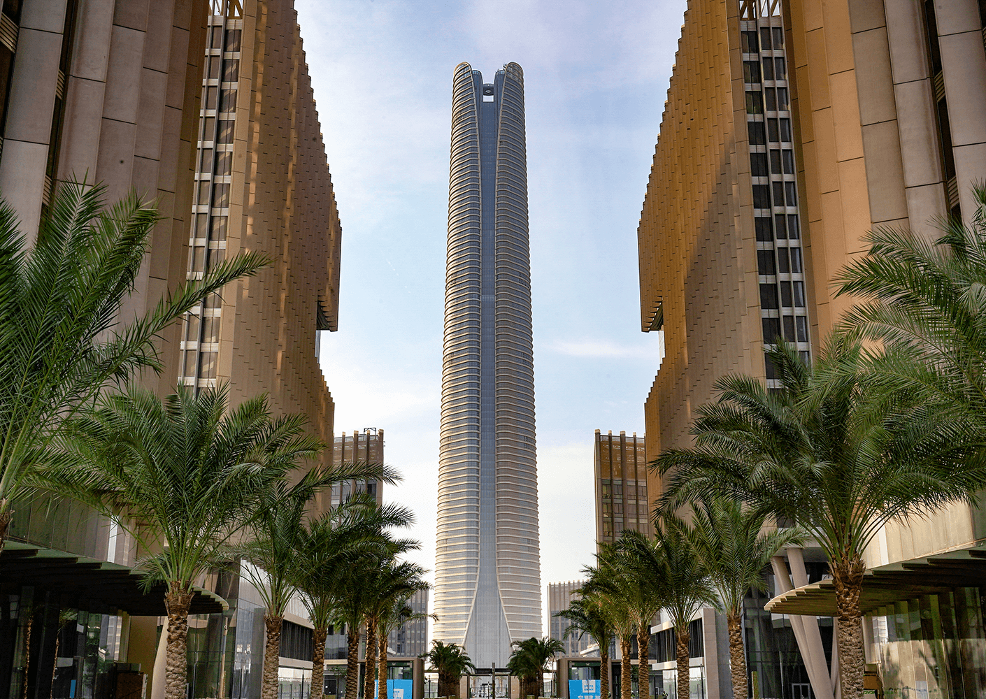Modern skyscraper between palm trees under clear sky.