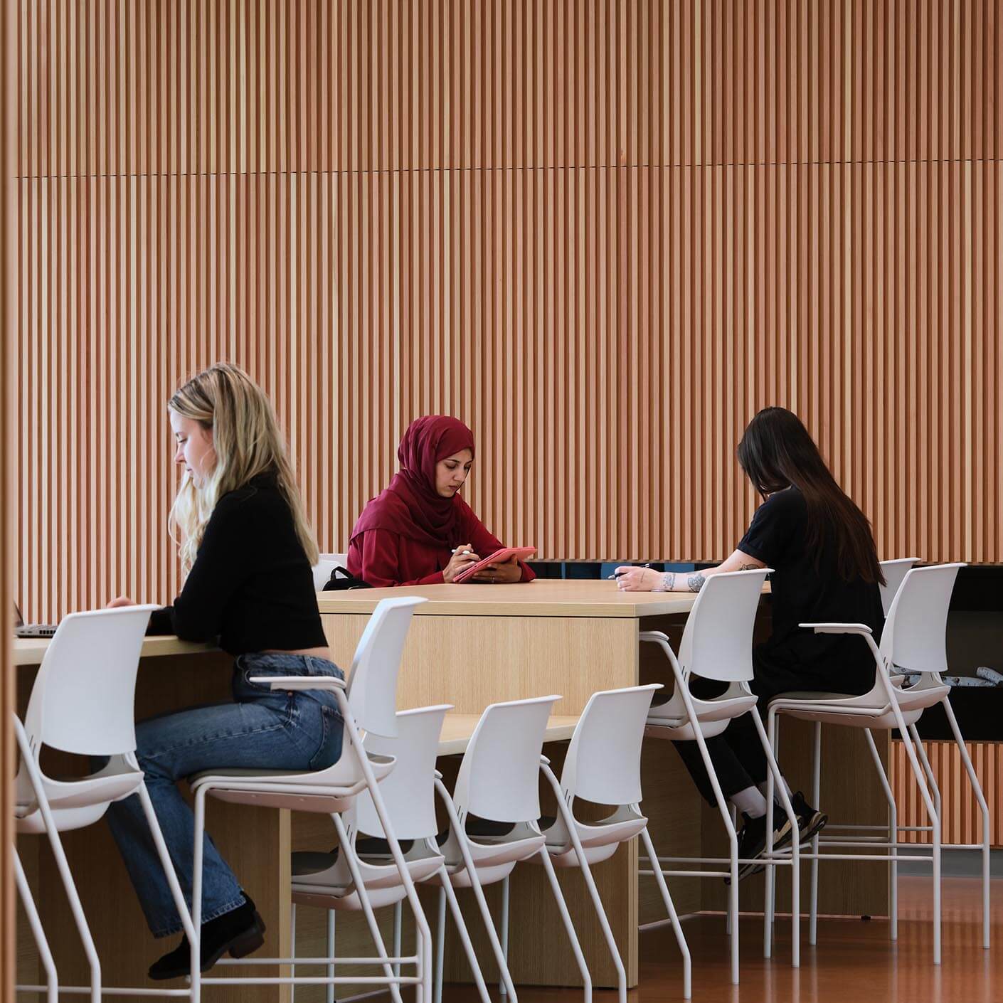 People studying at a wooden table, focused and engaged.