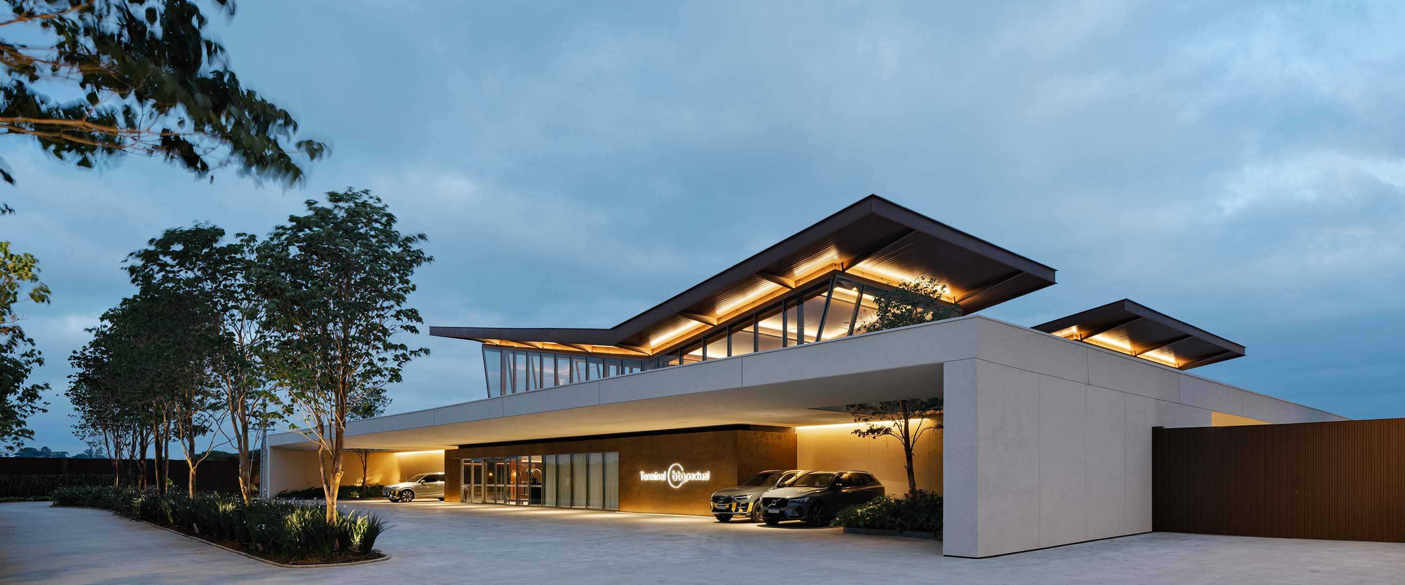Modern building exterior with illuminated roof and parked cars.
