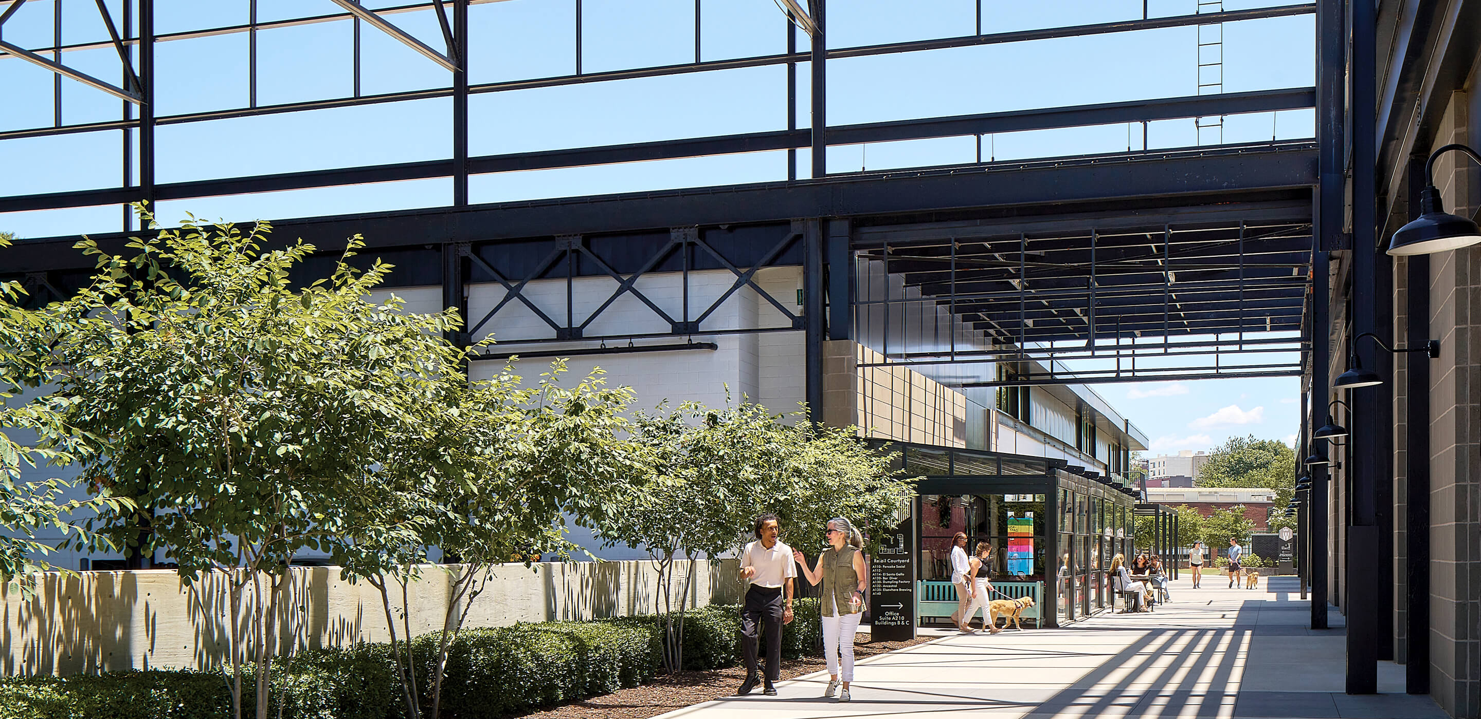 Open converted industrial space with walkway and people enjoying a sunny day.
