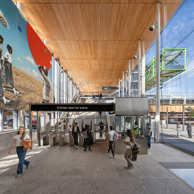 Modern train station entrance with colorful mural and passengers.