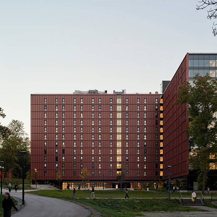 Red brick university building with pathways and trees at dusk.
