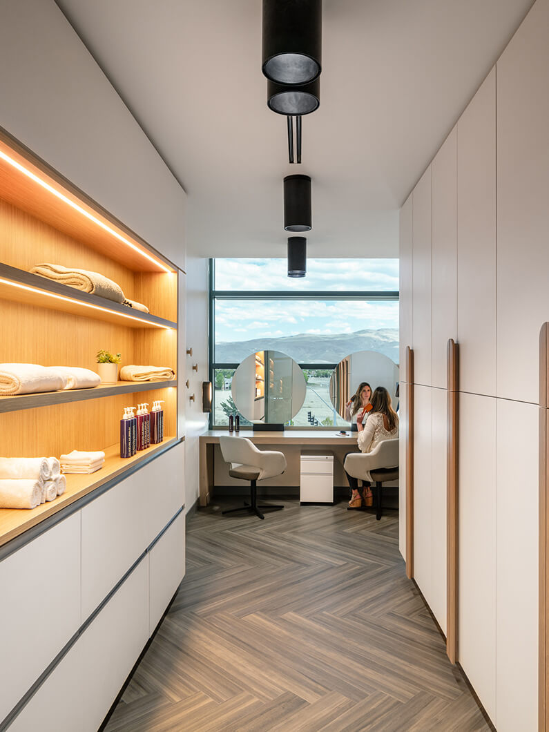 Modern salon area with large mirrors, cozy seating, and stylish shelving.