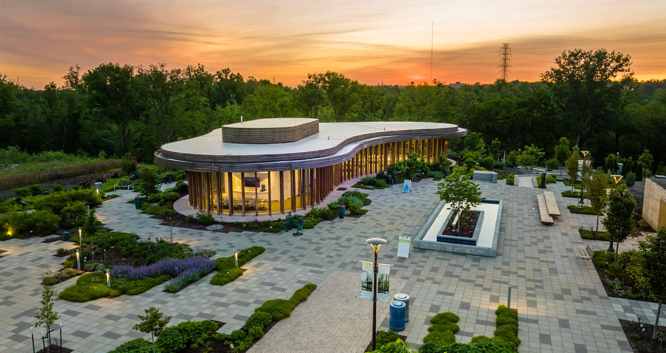 Modern building surrounded by landscaped gardens at sunset.