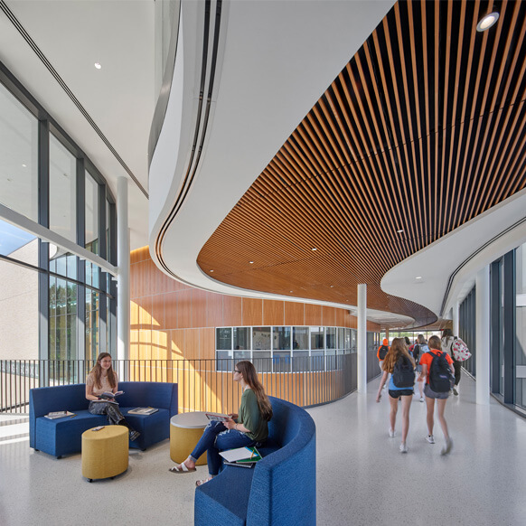 Modern school interior with students walking and studying in a bright, open space.