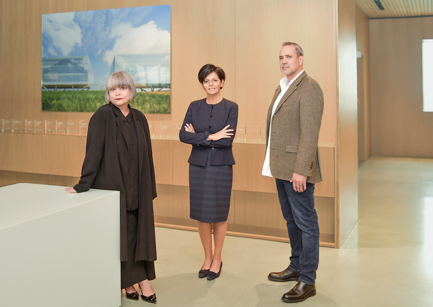 Three professionals in an office setting with modern architecture display.