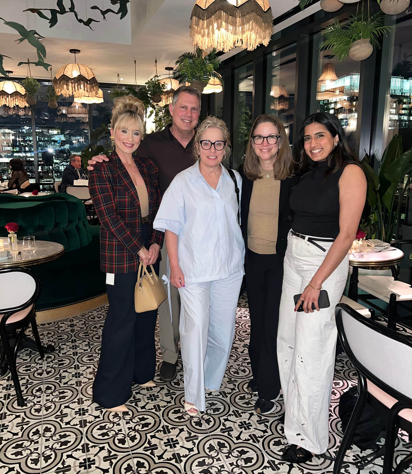 Five smiling people stand together in a restaurant.
