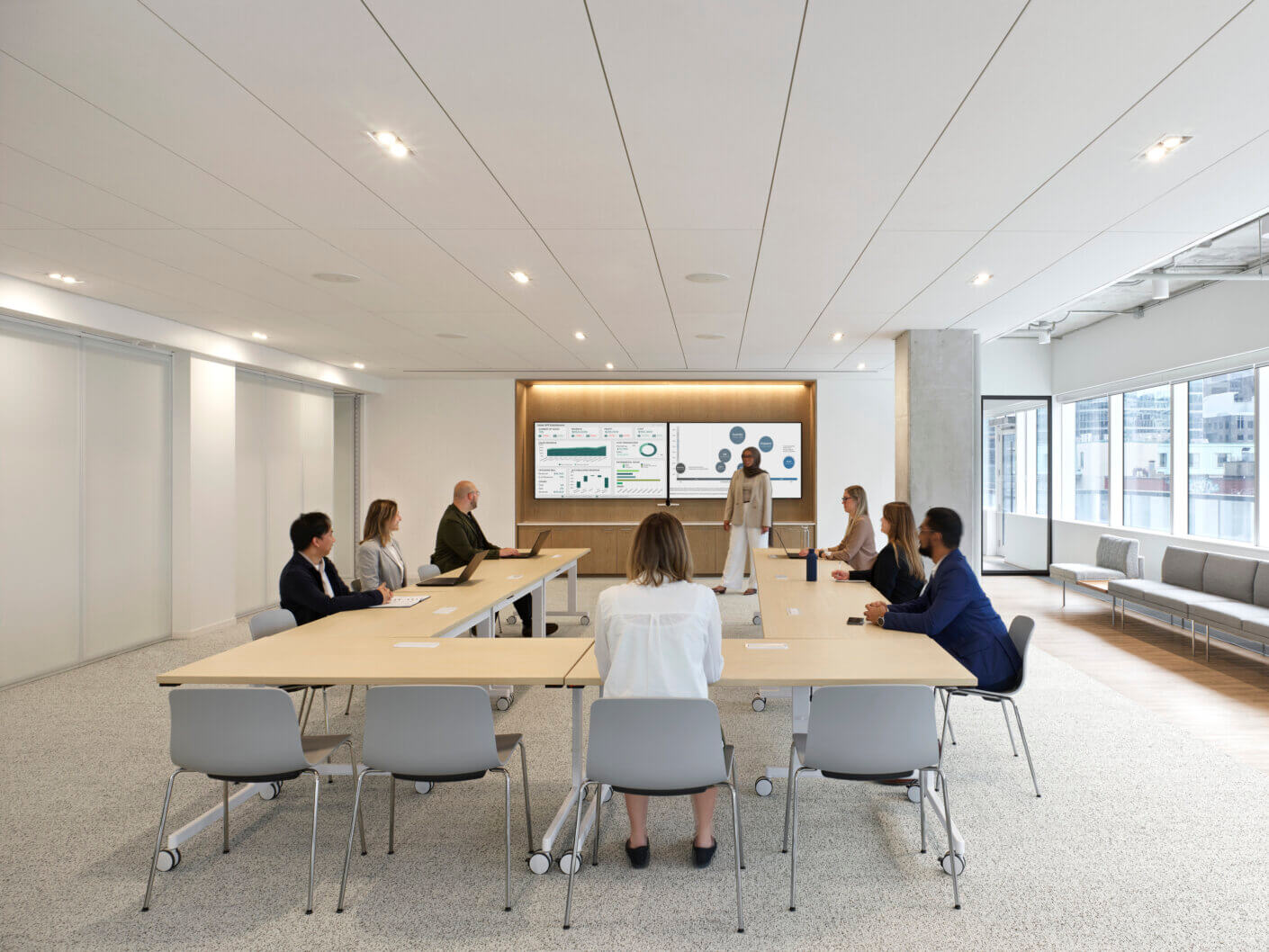 A collaborative meeting in a well-lit conference room with a large presentation screen, a long table, and engaged participants.
