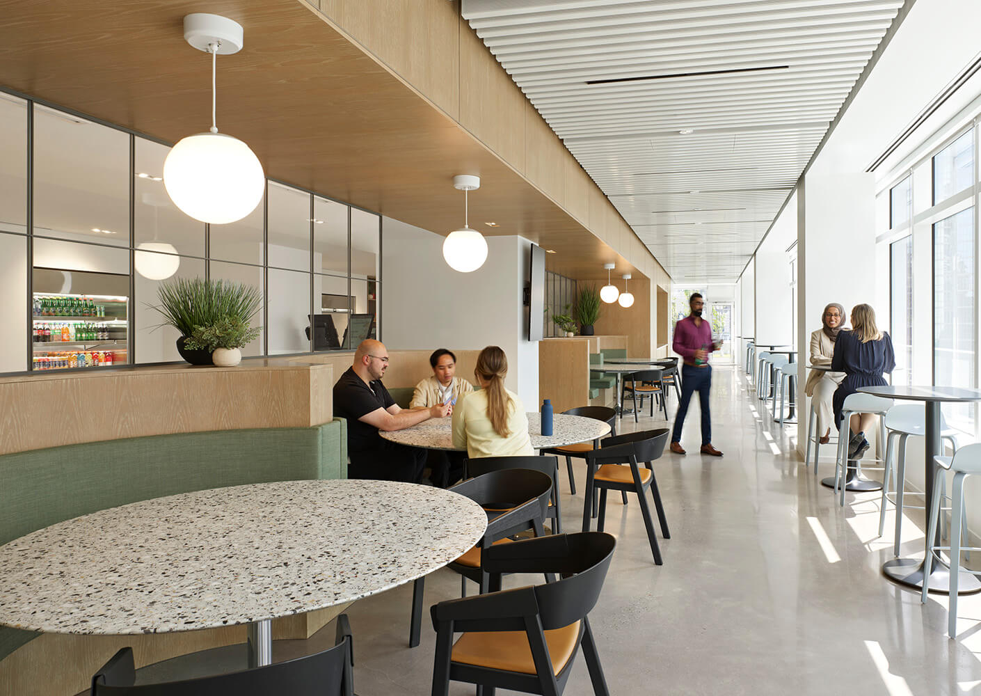 Contemporary café space with tables and seating. People engaging in conversation and enjoying the open, bright environment.