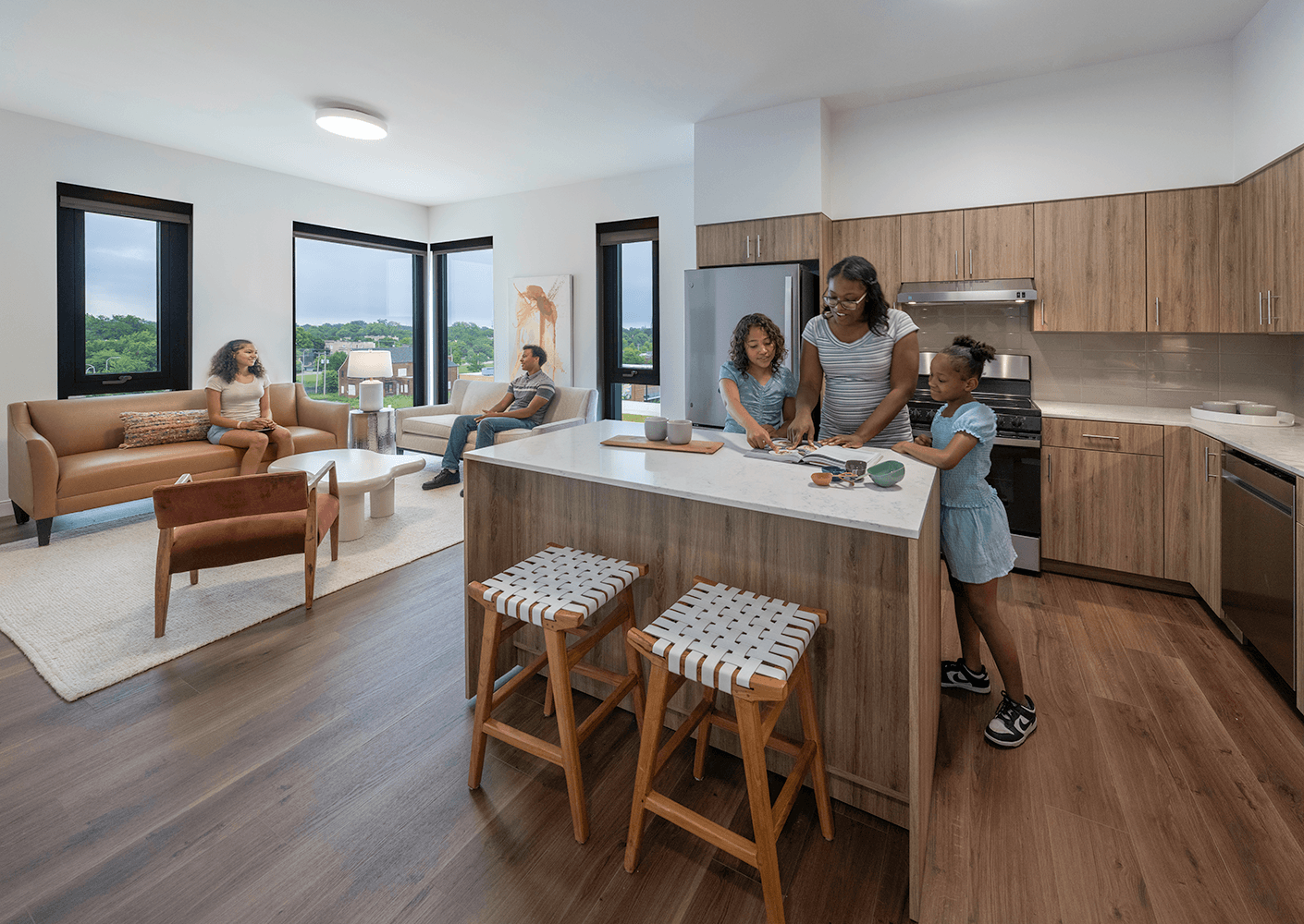 Family interacting in a bright, open kitchen and living area, featuring natural light, modern furniture, and a cozy atmosphere.