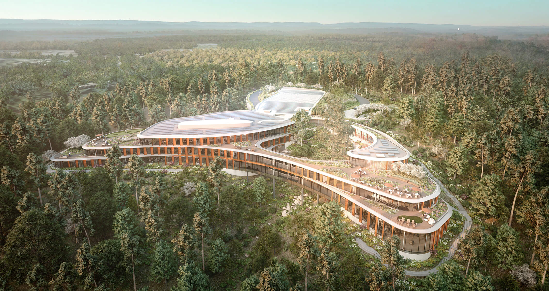 Aerial view of a unique architectural structure surrounded by dense forest, featuring terraces, gardens, and a sustainable design.