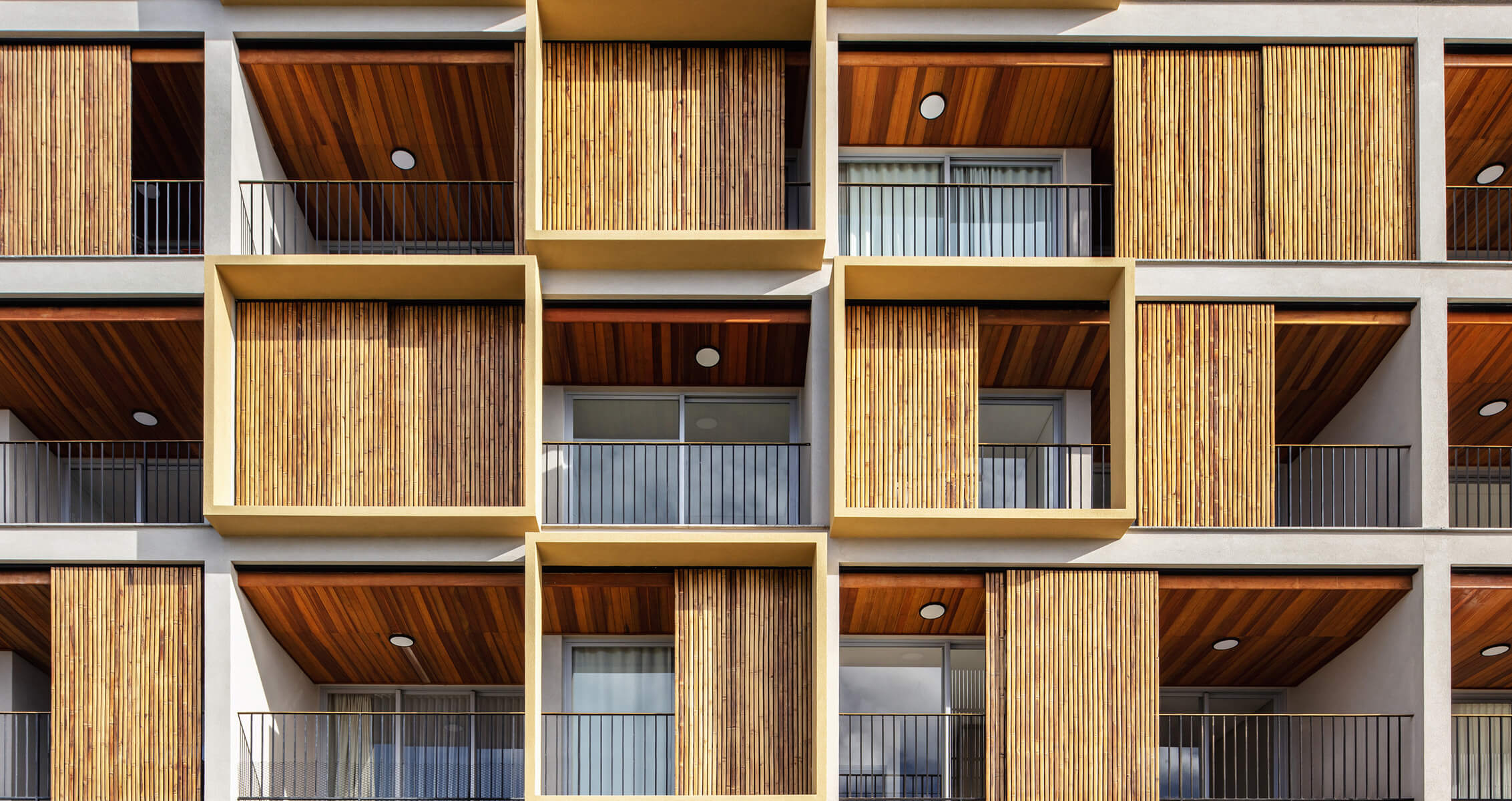 Facade of a building featuring distinct wooden paneling, balconies, and large windows, showcasing a geometric architectural design.