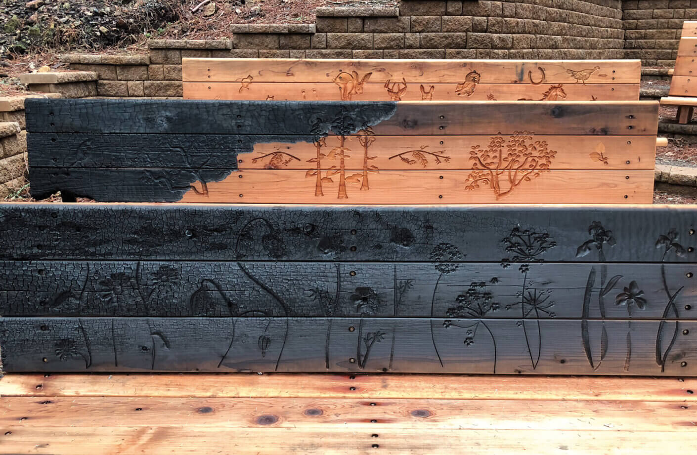 Three wooden panels featuring intricate engravings of wildlife and plants, showcasing contrasting finishes and textures.