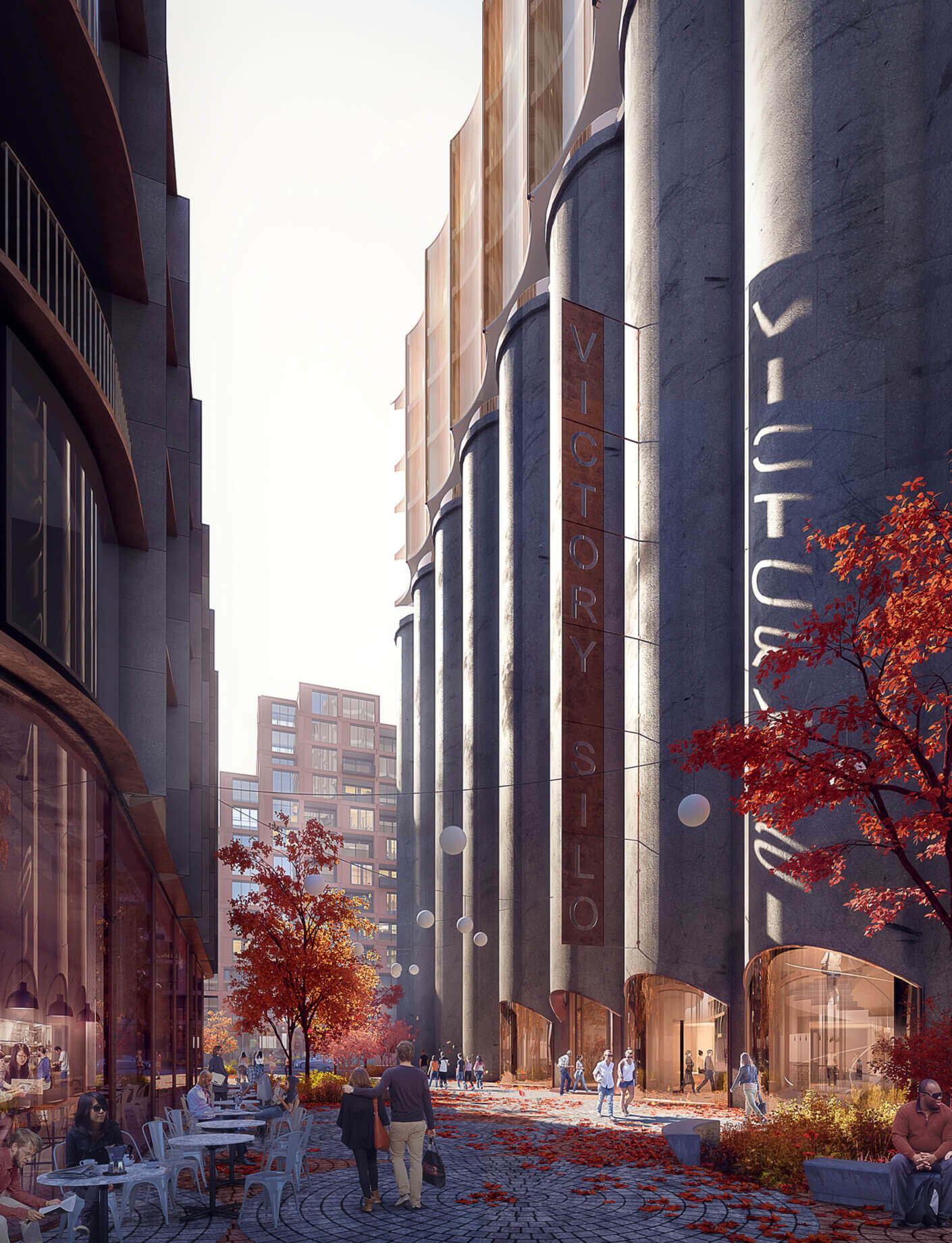 Urban plaza featuring Victory Silo, surrounded by modern architecture, outdoor dining, autumn foliage, and people walking along a cobblestone path.