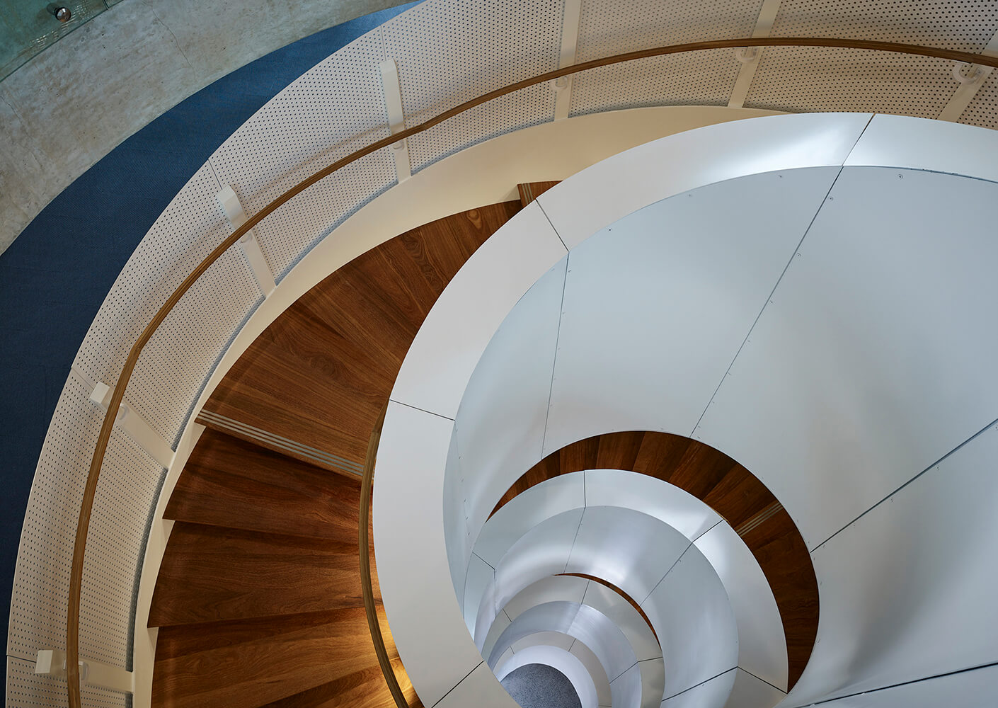 Spiral staircase with wooden steps and white railings. Overhead view showcasing the architecture and design of the space.