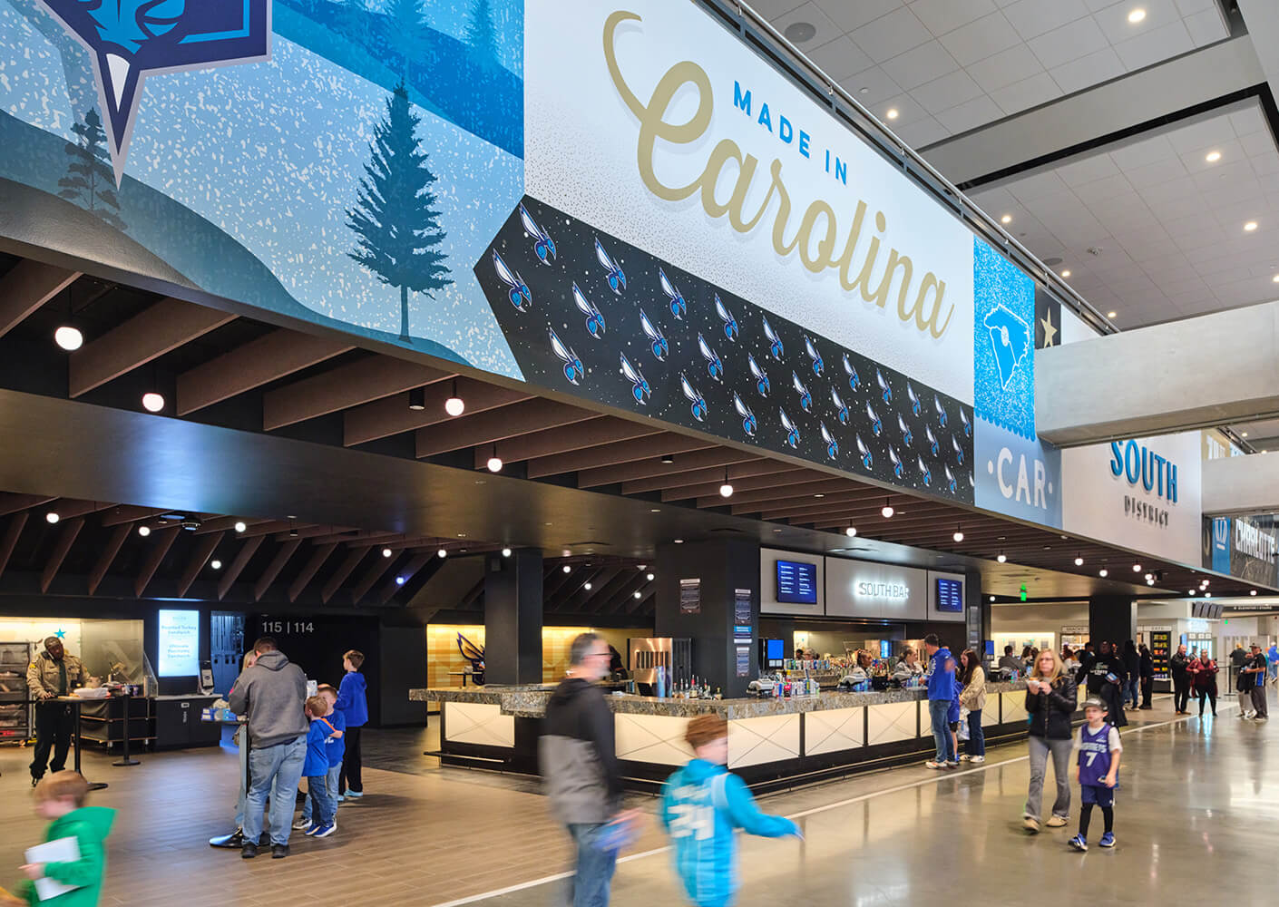 Interior of a venue featuring a large mural, an open concession area, and visitors interacting in a lively environment.