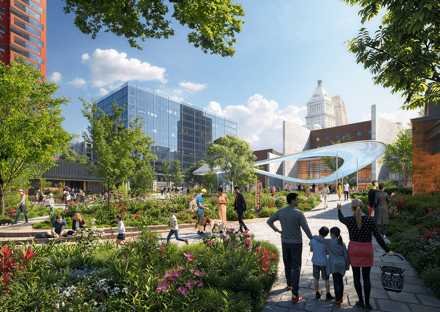 People walking through a landscaped urban area with flowers, pathways, and contemporary buildings under a clear sky.