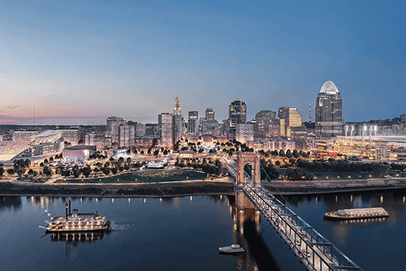 Aerial view of Cincinnati skyline at dusk, featuring the city’s buildings and the John A. Roebling Suspension Bridge over the Ohio River.