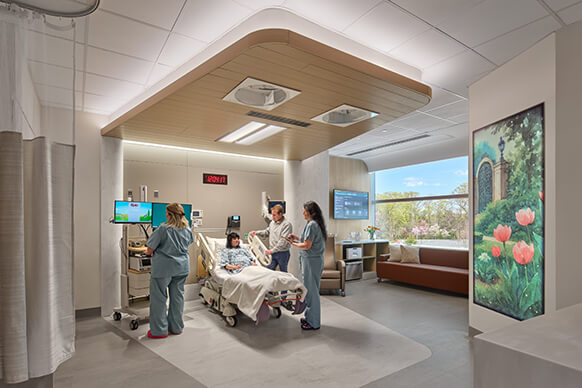Patient room featuring a medical team attending to a patient, with advanced equipment and a window providing natural light.